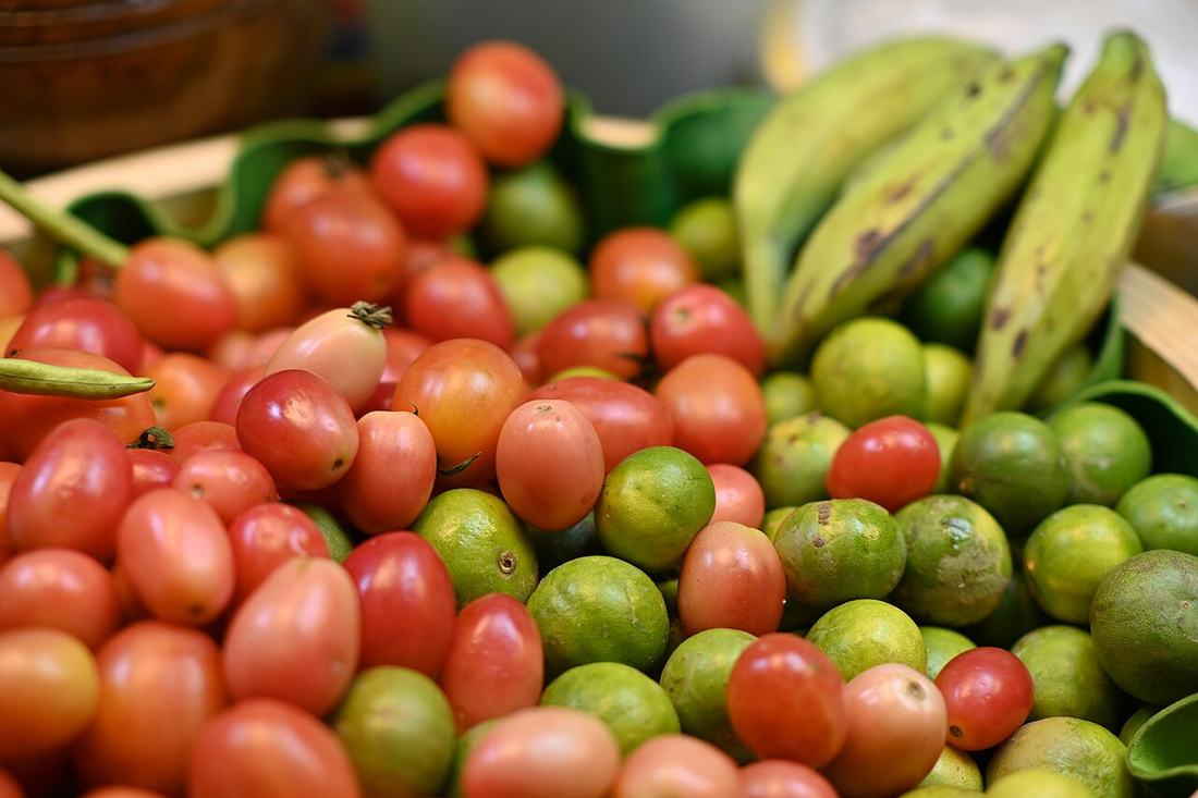 Tomatoes, limes, and bananas piled at a market, CC BY-SA 4.0